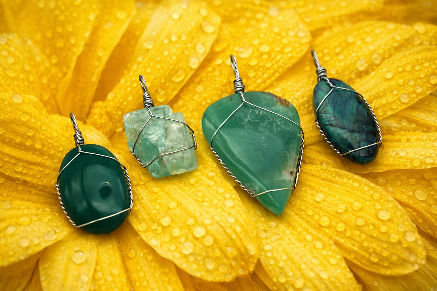 Green stone pendants on a yellow flower with water droplets